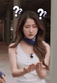 a woman wearing a white tank top and a blue scarf is making a funny face .