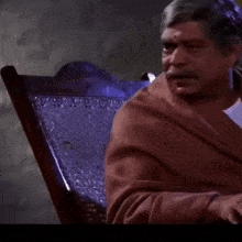 a man is sitting in a chair with the words lo ye to mut neh laga saala written below him