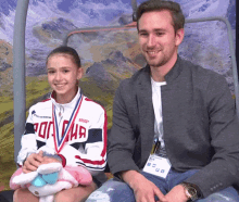 a man and a girl are sitting next to each other and the girl is wearing a medal that says russia