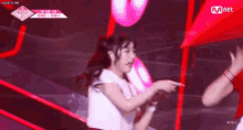 a girl in a white shirt is dancing on a stage in front of a mnet logo