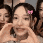 a close up of a girl making a heart shape with her hands .