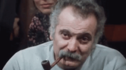 a man with a mustache is smoking a pipe in a bar .