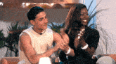 a man and a woman sitting on a couch clapping their hands