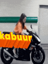 a woman is riding a motorcycle with the word kabuut written on it
