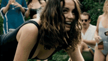 a woman in a black swimsuit is smiling while standing in front of a group of people