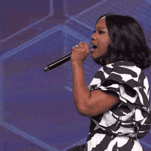 a woman singing into a microphone with a ring on her finger