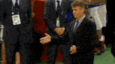 a man in a suit and tie stands in front of a group of people