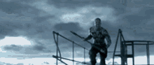 a man is holding a spear while standing on a fence .