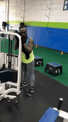 a woman is using a machine in a gym with the letter b on the wall behind her