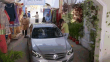 a silver car is parked in front of a store with a sign that says " no entry "