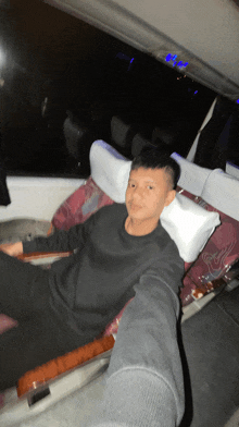 a boy in a black shirt sits in a chair with a white pillow on his head