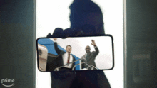 a person is holding a phone with a picture of two men on it and the word prime is on the bottom