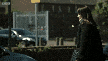 a woman in a suit walks past a brick wall