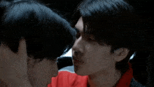 a close up of two men kissing each other in a dark room .