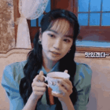a woman is holding a cup of tea in her hands
