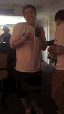 a man in a white shirt is standing in a room with other people