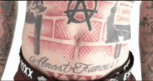 a man with a lot of tattoos has the word almost famous on his stomach