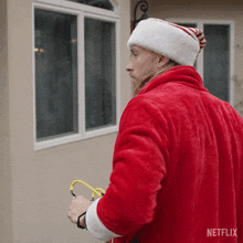 a man in a santa suit is standing in front of a window with a netflix logo on his back