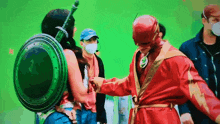 a woman in a wonder woman costume is shaking hands with a man in a flash costume .