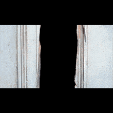 a man in a hat is peeking through a door frame