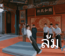 a man is doing a trick on a mat in front of a sign that says ' chinese ' on it