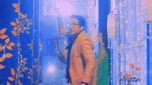 a man in a yellow coat is standing in a hallway with a blue background and the words toree on the bottom