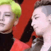 two men are standing next to each other with their eyes closed and one has green hair .