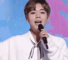 a young man is holding a microphone in his hand and singing into it .