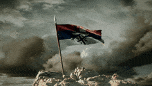 a flag on top of a rocky hill with a cloudy sky