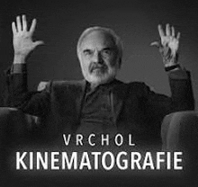 a man is sitting in a chair with his hands in the air .