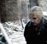 a man with long hair is standing in the snow looking down