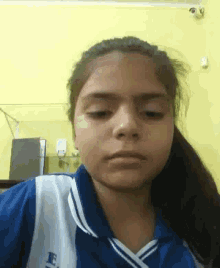 a young girl in a blue and white shirt is making a funny face