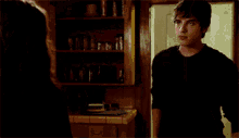 a man and a woman are looking at each other with an exit sign in the background