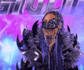 a woman with blue hair is wearing a mask and a costume that says thekamdreesen