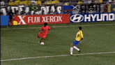 a soccer player kicks the ball in front of a fuji xerox sign