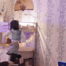 a little girl is dancing in a bedroom with a fan hanging on the wall .