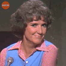a woman is smiling in front of a microphone with buzzr in the background