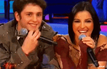 a man and a woman are smiling and holding microphones in front of them