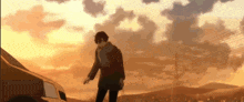 a man in a scarf is standing next to a car in front of a sunset sky .