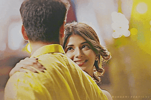 a man in a yellow shirt is hugging a woman in a red dress