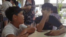 two boys sit at a table with one wearing a t-shirt that says ' abercrombie & fitch ' on it