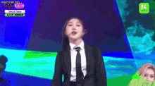 a woman in a suit and tie is singing into a microphone on a stage .