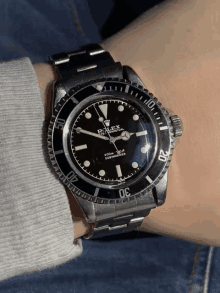 a person is wearing a rolex submariner watch