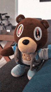 a brown teddy bear wearing a blue jacket and a shirt with the letter b on it