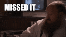 a man with a beard is sitting in front of a tv with the words missed it above him
