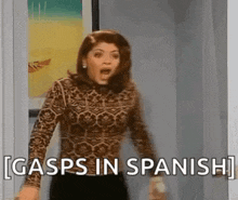 a woman is standing in a doorway with her mouth open and the words gasps in spanish written on the wall behind her .