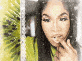 a woman in a green shirt is biting a piece of fruit