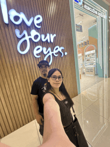 a man and a woman standing in front of a store that says love your eyes