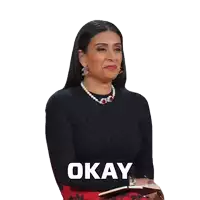 a woman wearing a black sweater and a pearl necklace is holding a notebook and saying okay .