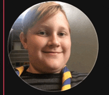 a young boy wearing a striped shirt and a yellow and blue scarf smiles for the camera